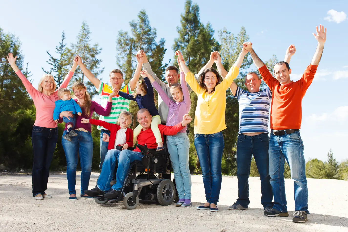 Diverse group of people standing with arms up