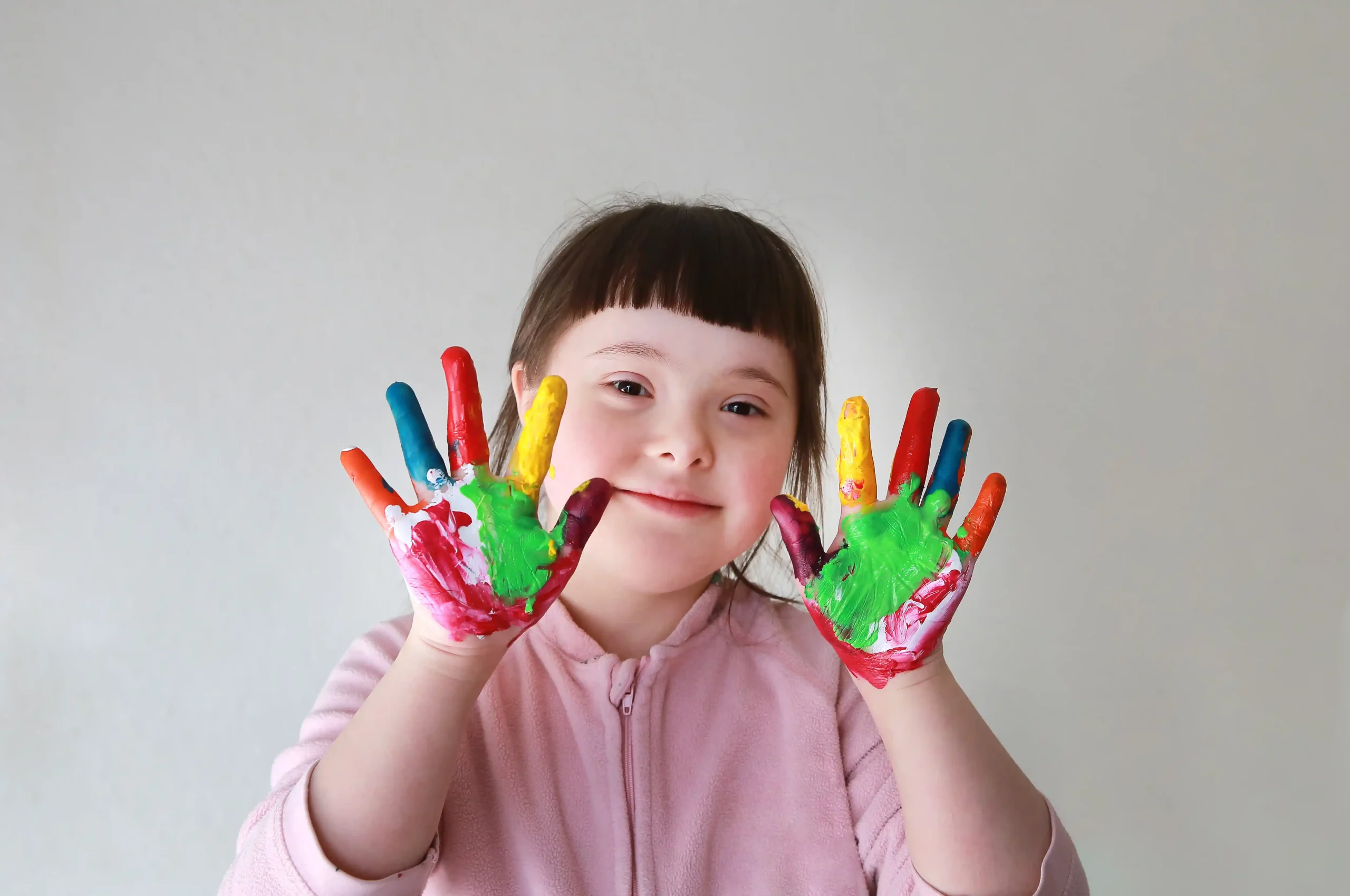 Disabled girl with down syndrome holding up painted hands